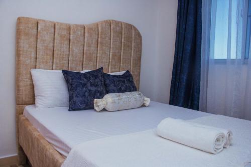 a bed with a headboard and two towels on it at Joyous Homes in Mombasa