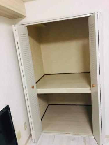 einen Schrank mit einer offenen Tür in einem Zimmer in der Unterkunft ASUKA STUDIO l 日の出町 in Yokosuka