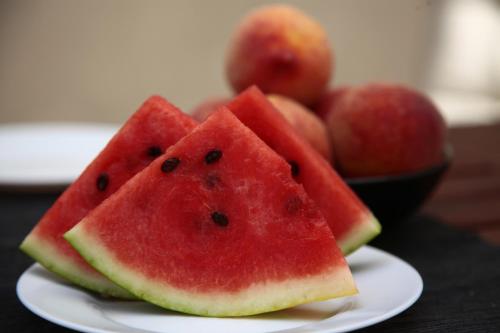 two slices of watermelon on a plate with a bowl of fruit at B&B Massimo Inn in Palermo