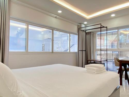 1 dormitorio con 1 cama blanca, escritorio y ventanas en Best Studio Room Near Ben Thanh Market, en Ho Chi Minh