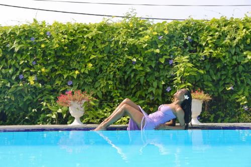 a woman sitting on the side of a swimming pool at Amanda Beach Resort in Pasikuda