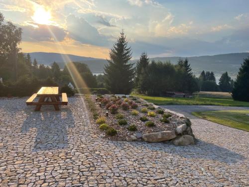 a wooden bench sitting in a garden with the sun setting at Apartmány HÁJOVNA Lipno in Loučovice