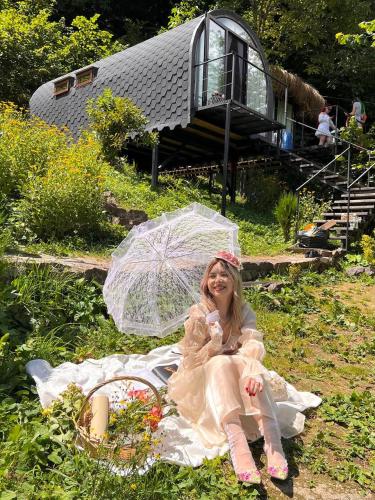 a woman in a dress sitting on a blanket with an umbrella at Woodhide - Cottages near Batumi, Georgia in Zeda Ch'khutunet'i
