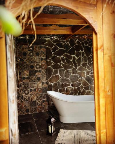 a bath tub in a bathroom with a stone wall at Woodhide - Cottages near Batumi, Georgia in Zeda Ch'khutunet'i