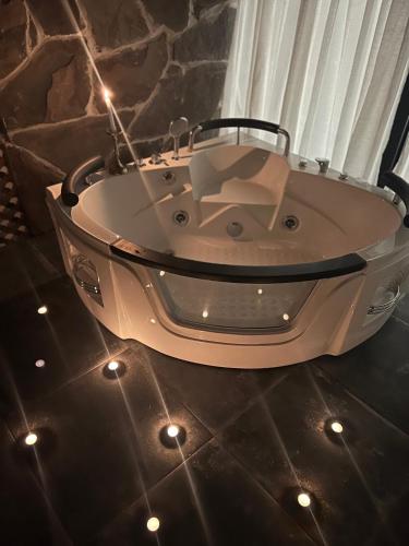 a white bath tub sitting on a floor with lights at Woodhide - Cottages near Batumi, Georgia in Zeda Ch'khutunet'i
