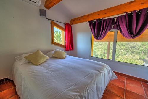 a bedroom with a white bed and two windows at Casa Vecchia rooms + apartments in Calvi