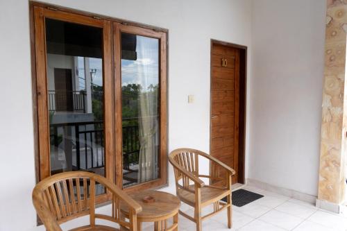 a porch with two chairs and a table and a window at Kayuma House Canggu in Canggu