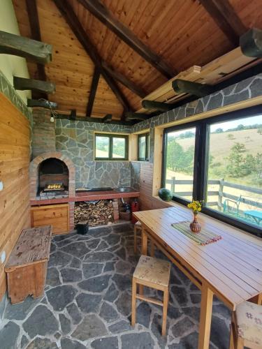Zimmer mit einem Holztisch und einem Steinkamin. in der Unterkunft Casa Mila Zlatibor in Zlatibor