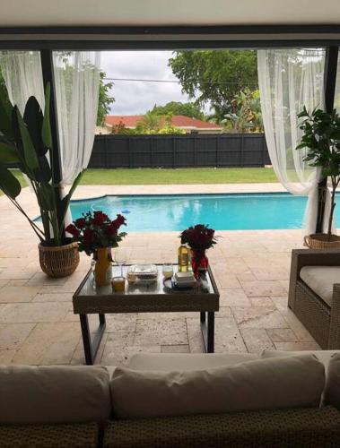 a living room with a couch and a table next to a pool at Spacious 4 Bedroom 3 Bathroom House with Heated Pool and Outdoor Shower close to FFL Airport and Cruise Port in Plantation