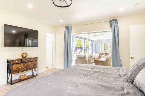 a bedroom with a bed and a dresser with a television at Spacious 4 Bedroom 3 Bathroom House with Heated Pool and Outdoor Shower close to FFL Airport and Cruise Port in Plantation