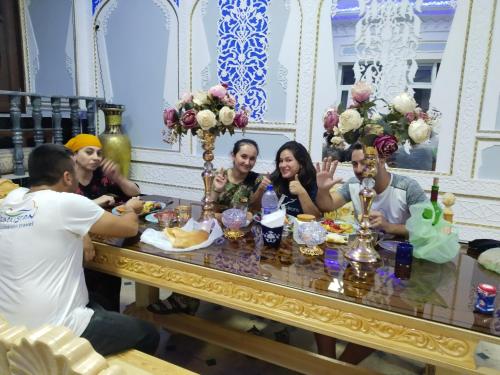 een groep mensen die rond een tafel zitten met eten bij Hotel Rizqiro'z Boutique in Bukhara