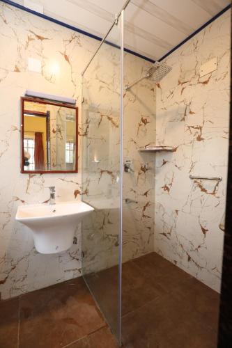 a bathroom with a sink and a glass shower at Hotel Silver Oak in Ooty