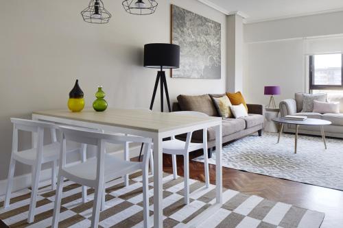 sala de estar con mesa blanca y sillas en Duke by FeelFree Rentals, en San Sebastián