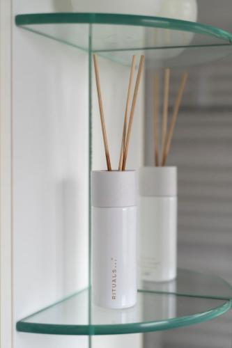 two white vases on a glass shelf with sticks at Exclusive 2-Room-City-Apartment - Contactless Check-in in Hannover