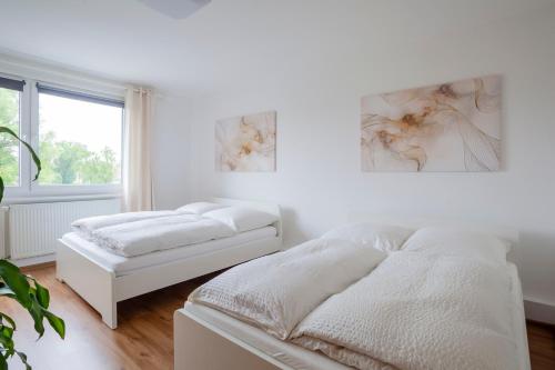 a white bedroom with two beds and a window at Exclusive 2-Room-City-Apartment - Contactless Check-in in Hannover