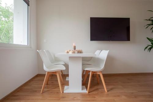 a white table with white chairs and a tv on a wall at Exclusive 2-Room-City-Apartment - Contactless Check-in in Hannover