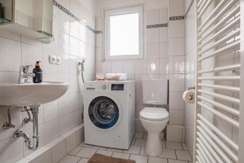 La salle de bains blanche est pourvue d'un lave-linge et d'un lavabo. dans l'établissement Exclusive 2-Room-City-Apartment - Contactless Check-in, à Hanovre