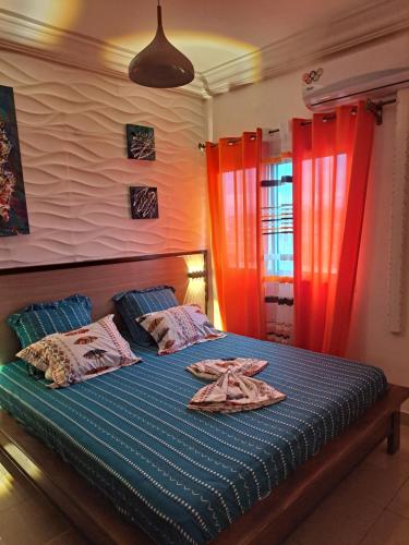 a bedroom with red curtains and a bed with towels on it at Chez Roland in Kribi