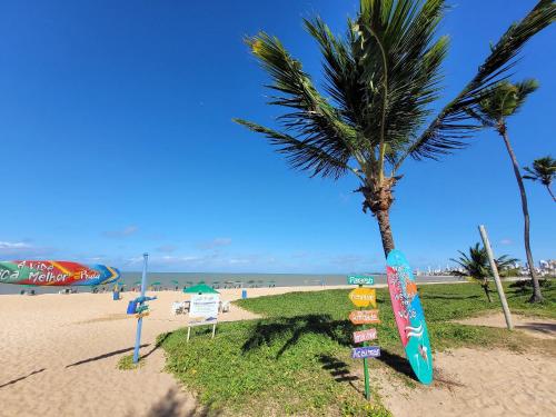 a palm tree on a beach with signs at Excelente Flat no Bessa a 50m da praia in Tambaú