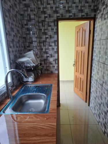 eine Küche mit einem Waschbecken und einer offenen Tür in der Unterkunft Chez Roland in Kribi