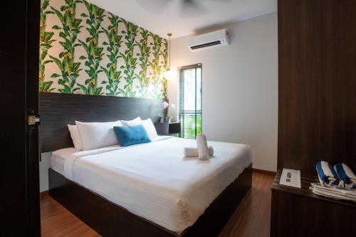 une chambre avec un grand lit blanc avec des oreillers bleus dans l'établissement Villa Renai Resort, à Bentong