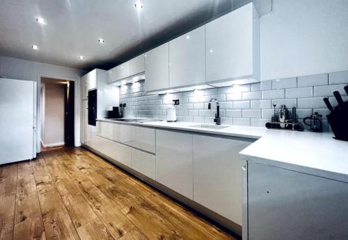 uma cozinha com electrodomésticos brancos e piso em madeira em Entire Modern House in Tamworth - 2 Double Beds + Free Parking em Tamworth