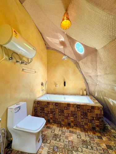 a bathroom with a toilet and a bath tub at Whoopers Boutique Resort Jibhi in Jibhi