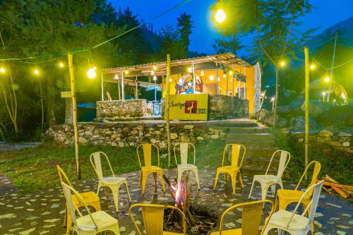 a group of yellow chairs sitting in front of a building at Whoopers Boutique Resort Jibhi in Jibhi