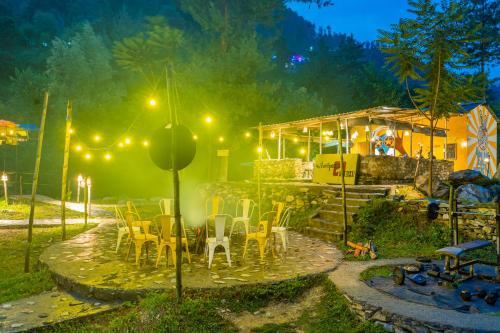 a group of tables and chairs in a yard at night at Whoopers Boutique Resort Jibhi in Jibhi