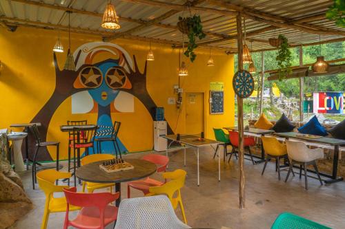 a restaurant with colorful chairs and tables in a room at Whoopers Boutique Resort Jibhi in Jibhi