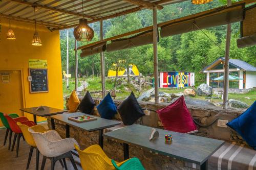 a restaurant with tables and chairs with a view at Whoopers Boutique Resort Jibhi in Jibhi