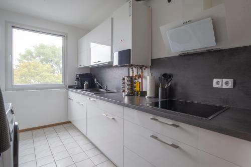 a kitchen with white cabinets and a window at Exclusive 2-Room-City-Apartment - Contactless Check-in in Hannover