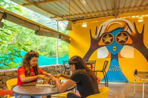 two people sitting at a table playing chess at Whoopers Boutique Resort Jibhi in Jibhi
