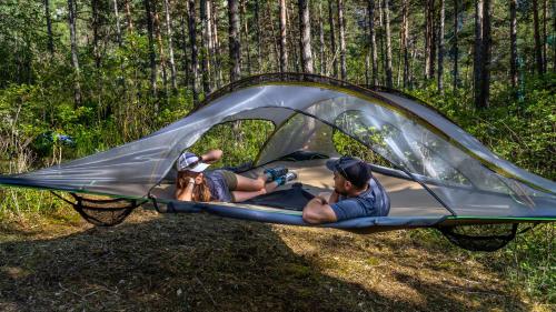 two people and a dog laying in a tent at Adventure Forest in Castellane
