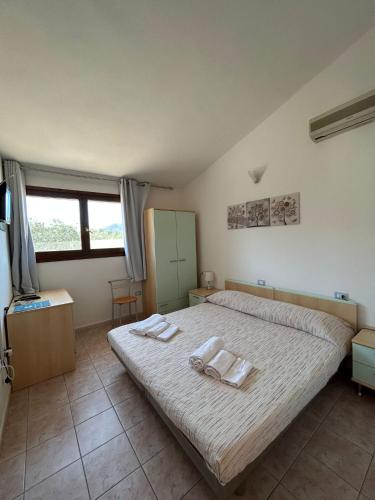 a bedroom with a bed with two towels on it at La Corte Degli Ulivi in Cardedu
