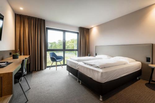 ein Hotelzimmer mit einem Bett und einem Schreibtisch in der Unterkunft i - PARK Hotel Klingholz in Reichenberg