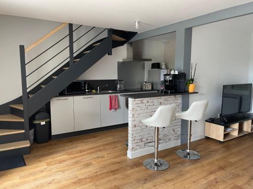 a kitchen with a staircase and white cabinets and chairs at Maison de 2 chambres proche A11 Ancenis, Logis du Château Rouge in Mésanger