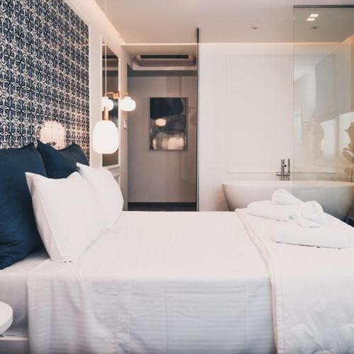 a bedroom with a large white bed and a tub at BLUE LUXURY SUITES in Preveza