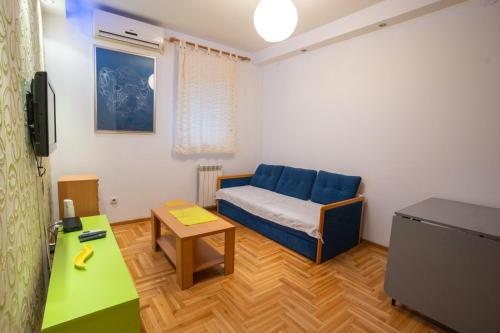 Una sala de estar con un sofá azul y una mesa. en Lorono Kosta, en Belgrado