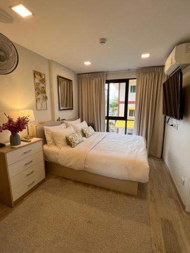 una camera da letto con un letto grande e una televisione di Marvest Condo Hua Hin a Hua Hin
