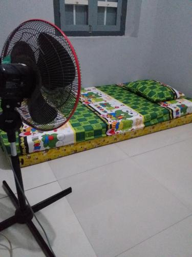 un ventilador en un puesto junto a una cama en HOMESTAY SYARIAH GRIYO VIEW SAWAH, en Godean