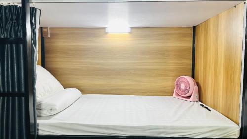 a bed with a wooden head board and a pink alarm clock at A Páo Hostel Mộc Châu in Mộc Châu