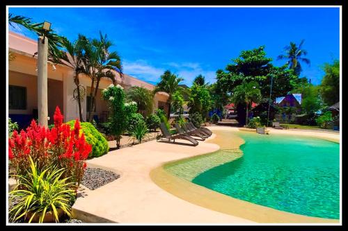 una piscina in un resort con panchine e fiori di Imagine-Bohol a Panglao