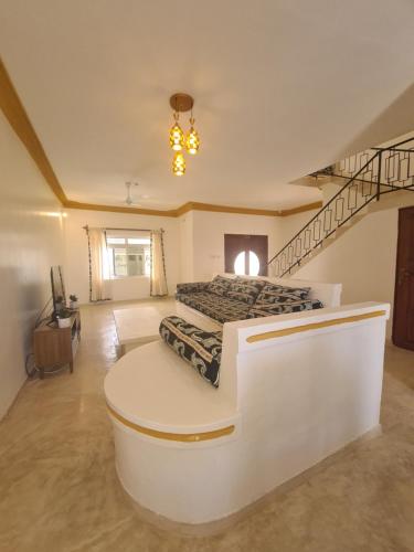 a large room with a staircase and a bed at Linda's Little Lincoln in Watamu