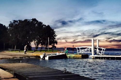 a boat is docked at a dock on the water at Waterview luxury hideaway, 2 min walk to all, pool in The Entrance