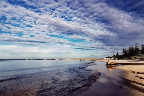 a beach with a cloudy sky and the water at Waterview luxury hideaway, 2 min walk to all, pool in The Entrance