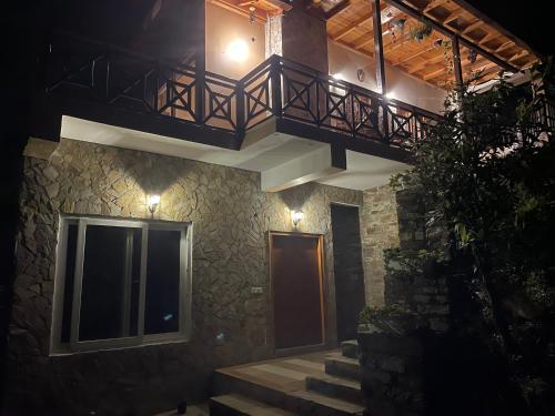 a building with a staircase and a balcony on it at Francolin Lodge-Farmstay @ Darima in Mukteswar
