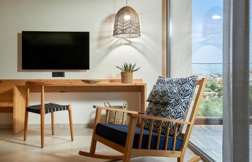 a room with a desk with a television and a chair at Sentido Amounda Bay in Amoudara Herakliou