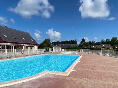 a large swimming pool with blue water at Chalet 6 pers avec piscine in Cabourg