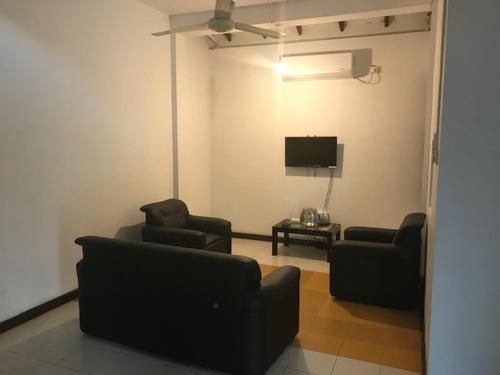 a living room with two chairs and a tv at Serene Holiday Home in Pannipitiya
